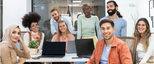 group of professionals stitting around a desk smiling at the camera