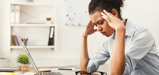 a person with the hands on the face looking at a laptop