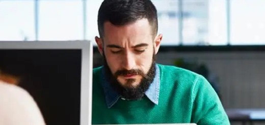 a man with a beard looking at a computer screen