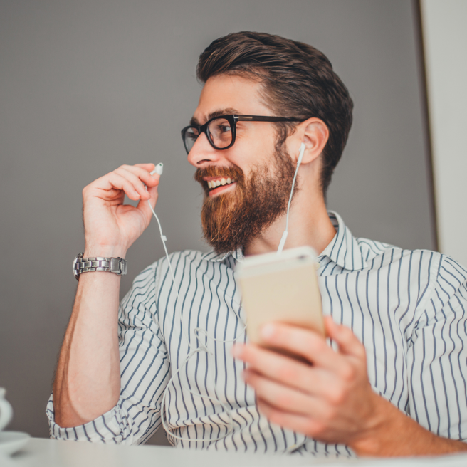 a man with a beard and glasses holding a phone